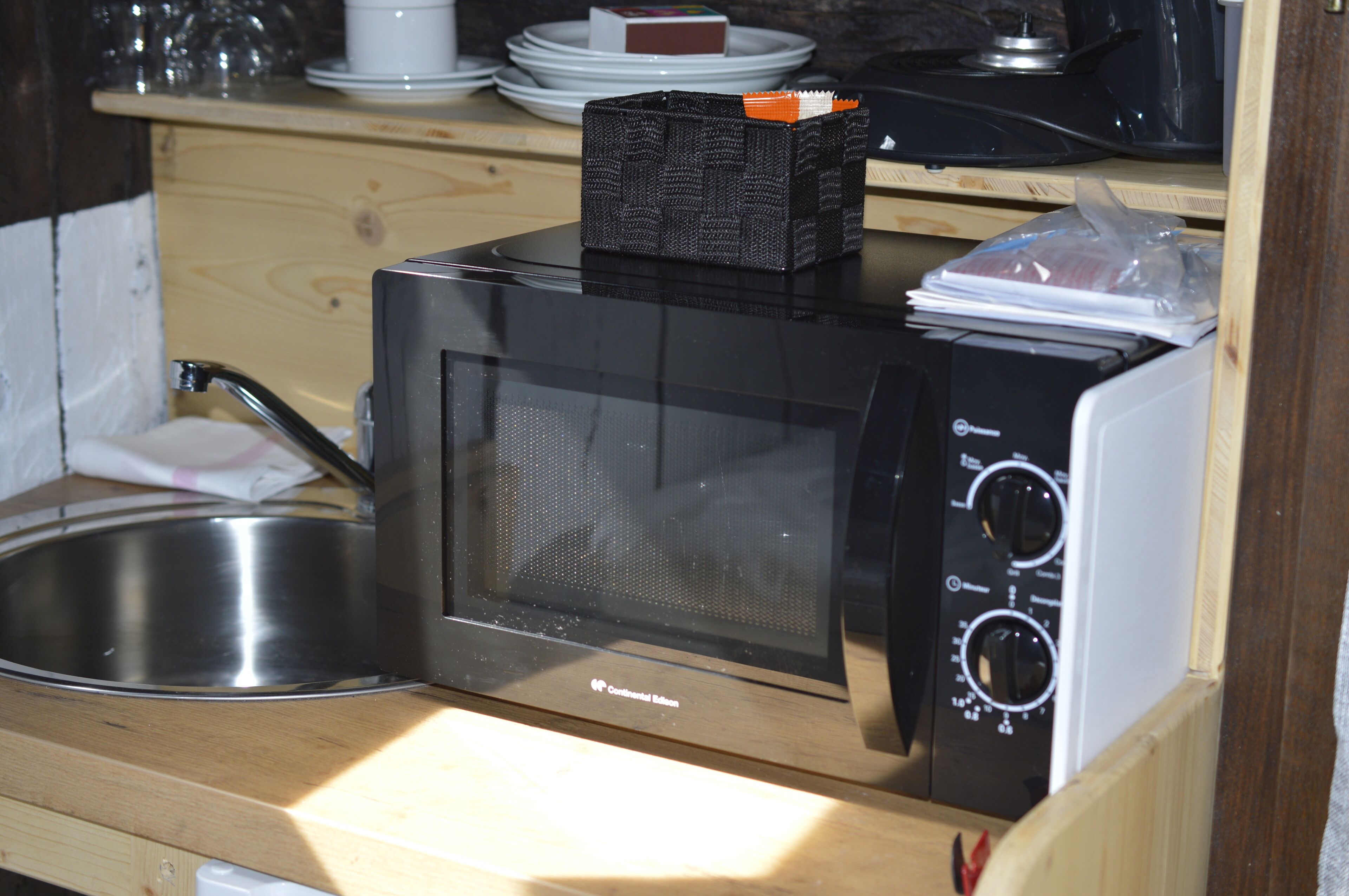 A compact kitchen with a microwave, sink, and wooden cabinets.