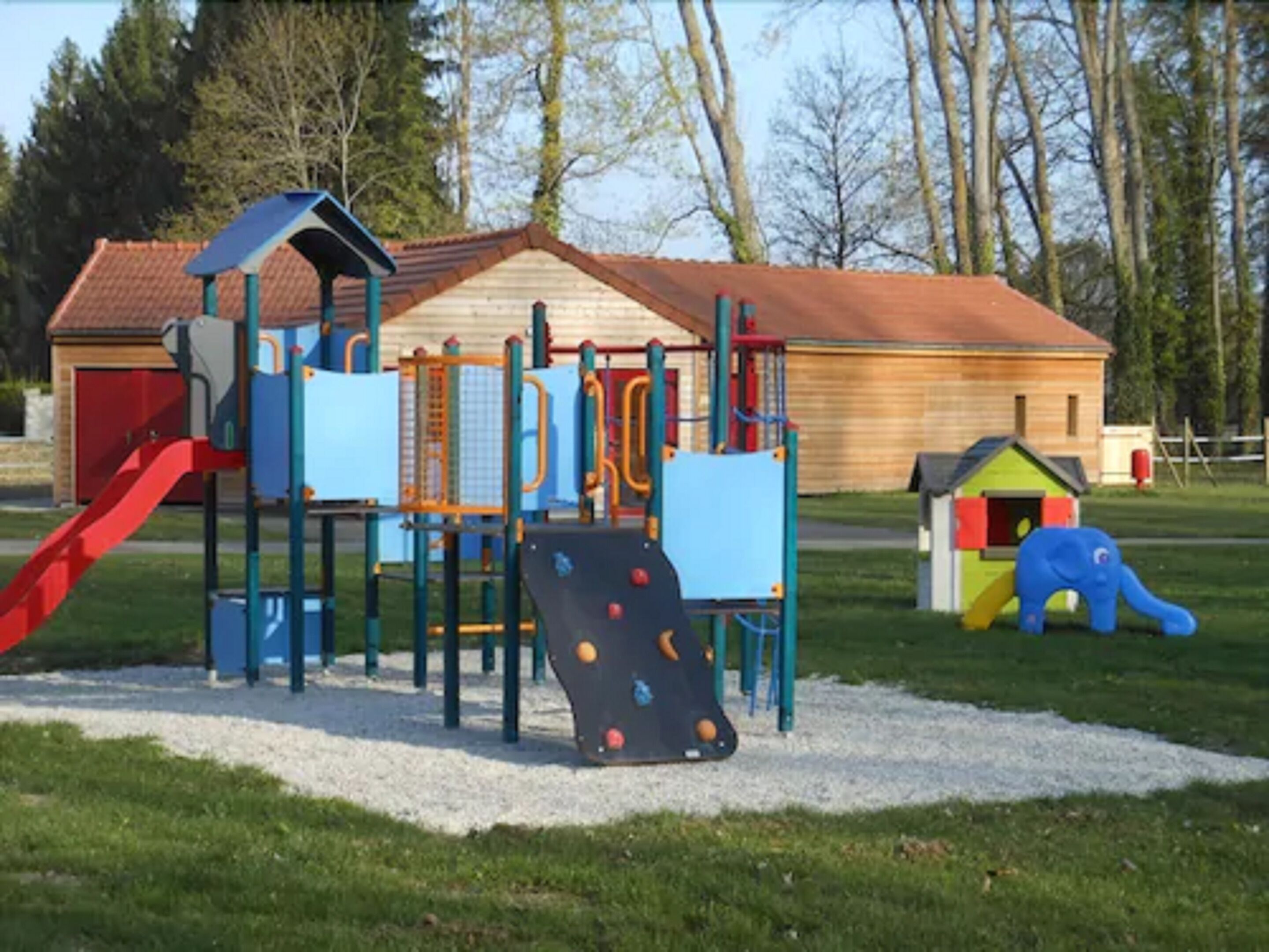A playground with climbing structures, slides, and a small house.