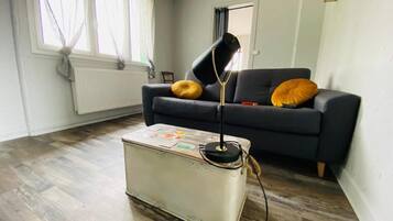 Un salón con sofá, dos cojines amarillos, una radio antigua y un radiador.