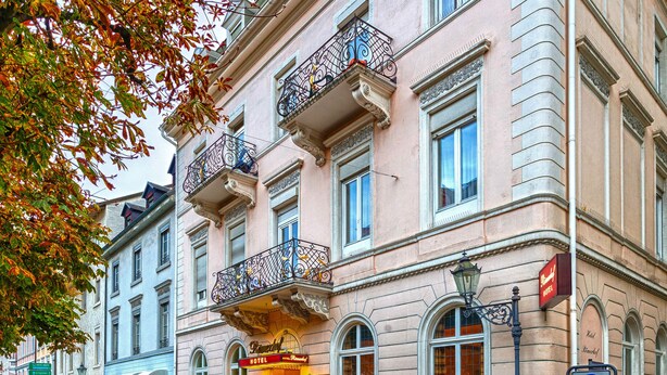 A historic building with a classic facade, multiple balconies, and a prominent entrance with a sign. - Hotel Römerhof (Baden-Baden)