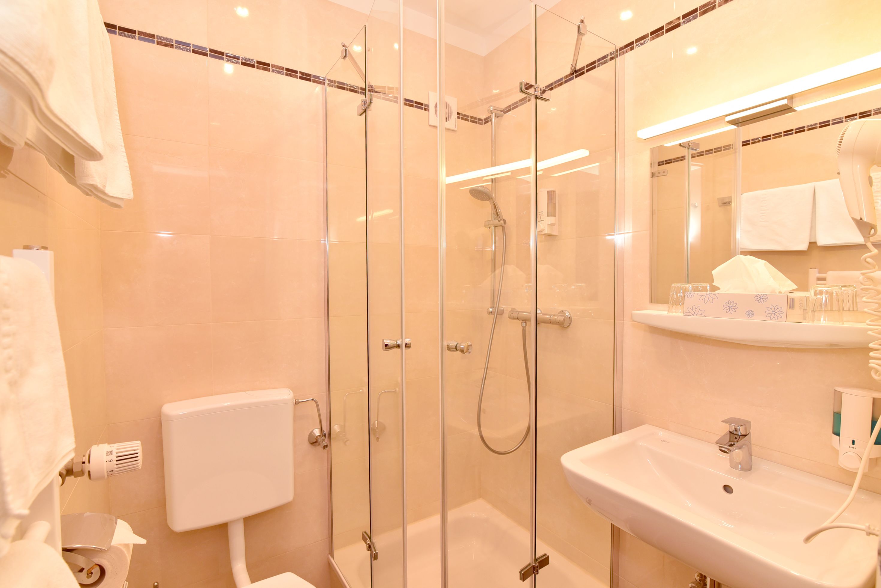A modern bathroom with a glass-enclosed shower, a white sink, and a mirror above the sink.