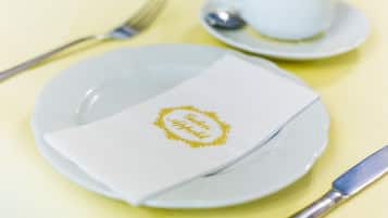 A neatly set table with a plate, napkin, cup, and spoon.