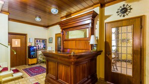 A reception area with a wooden reception desk, a clock, and a door with a glass panel. - Hotel Römerhof (Baden-Baden)