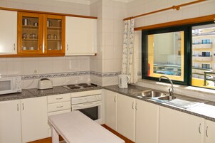 A kitchen with white cabinets, a microwave, a toaster, and a sink.