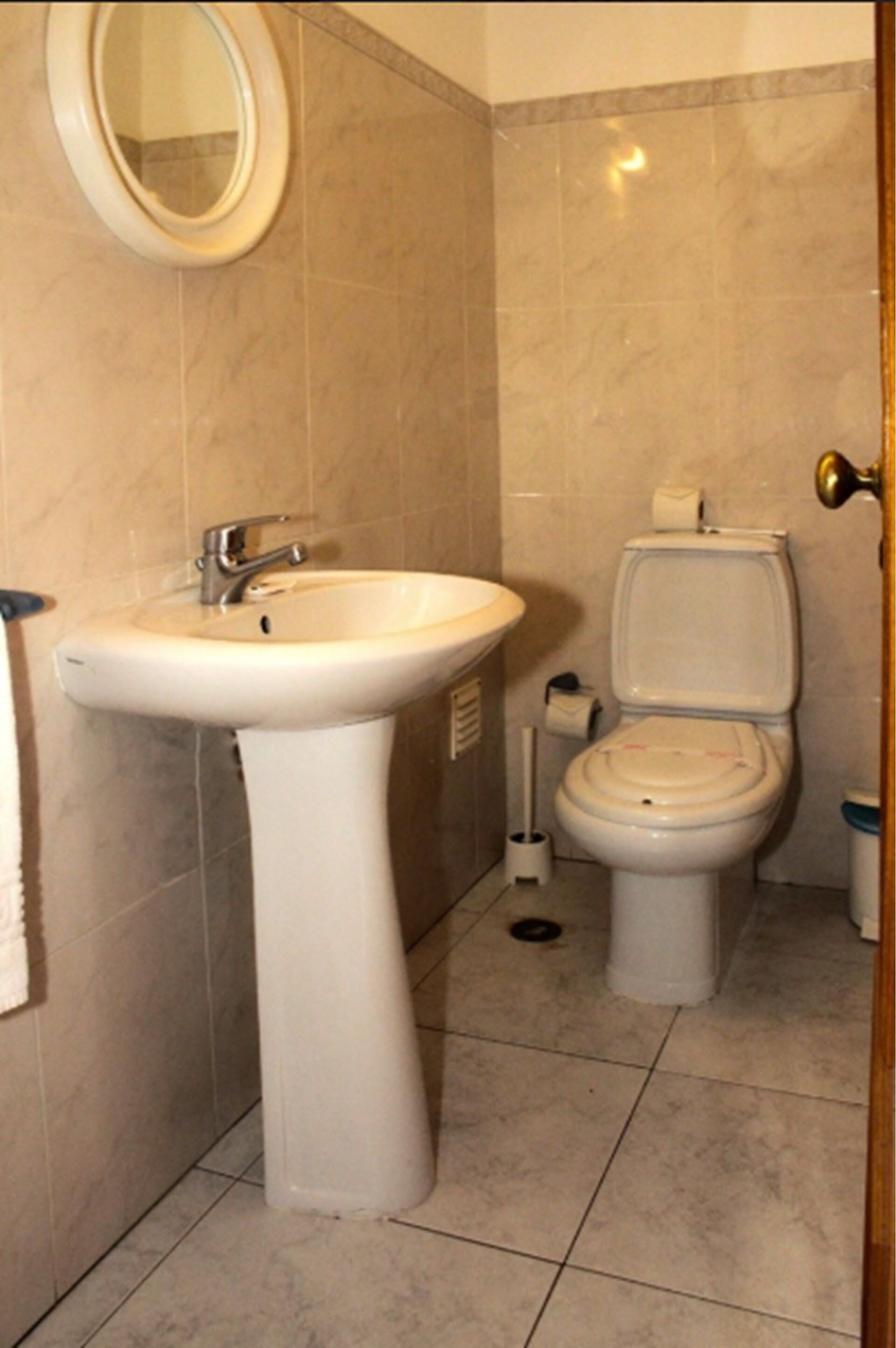 Ein Badezimmer mit einem Standwaschbecken, einer Toilette und einem Spiegel.