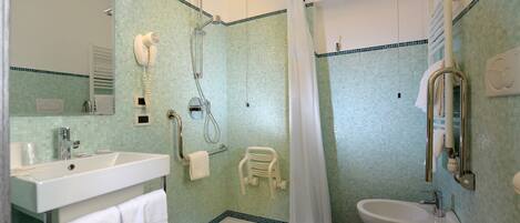 A bathroom with a shower, sink, and bidet.