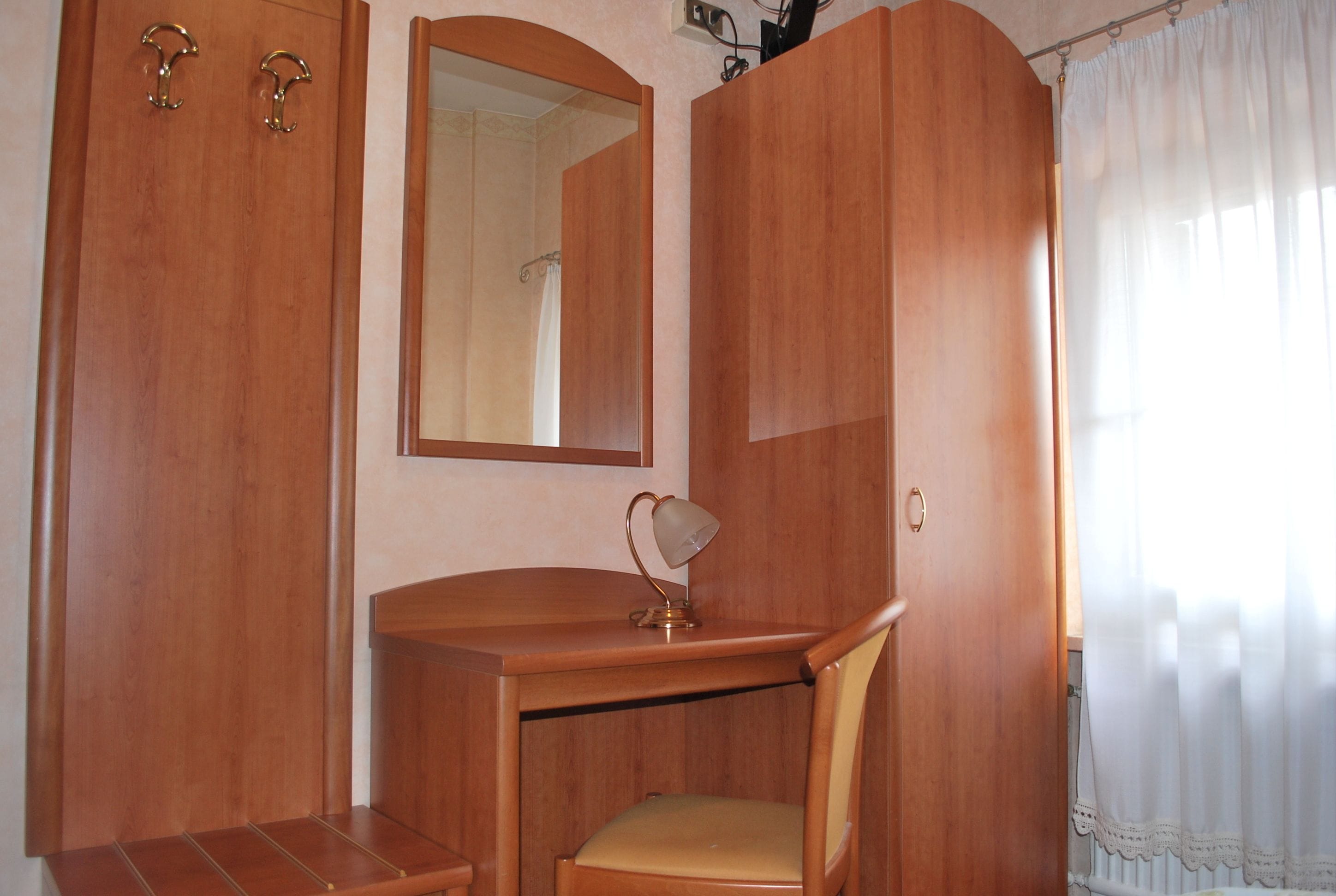 Un escritorio de madera con una silla, un espejo y un armario de dos puertas.