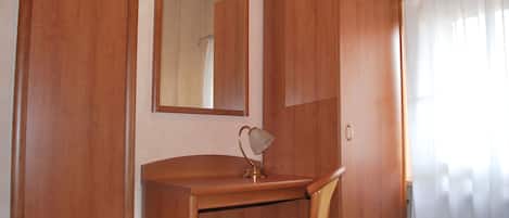 Un escritorio de madera con una silla, un espejo y un armario de dos puertas.