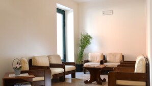 A living room with two sofas, a coffee table, a bookshelf, and a large potted plant. - Hotel Siena (Verona)