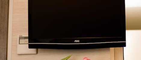 Televisor de pantalla plana montado en una pared con un estante de madera debajo.