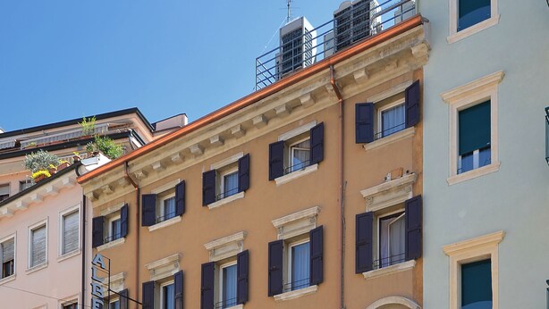 A hotel with a classic facade, multiple windows, and a sign indicating it is a hotel. - Hotel Siena (Verona)