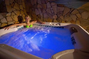 A person in a hot tub with a stone wall background.