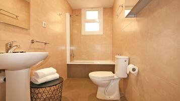 A compact bathroom with a sink, toilet, and shower.