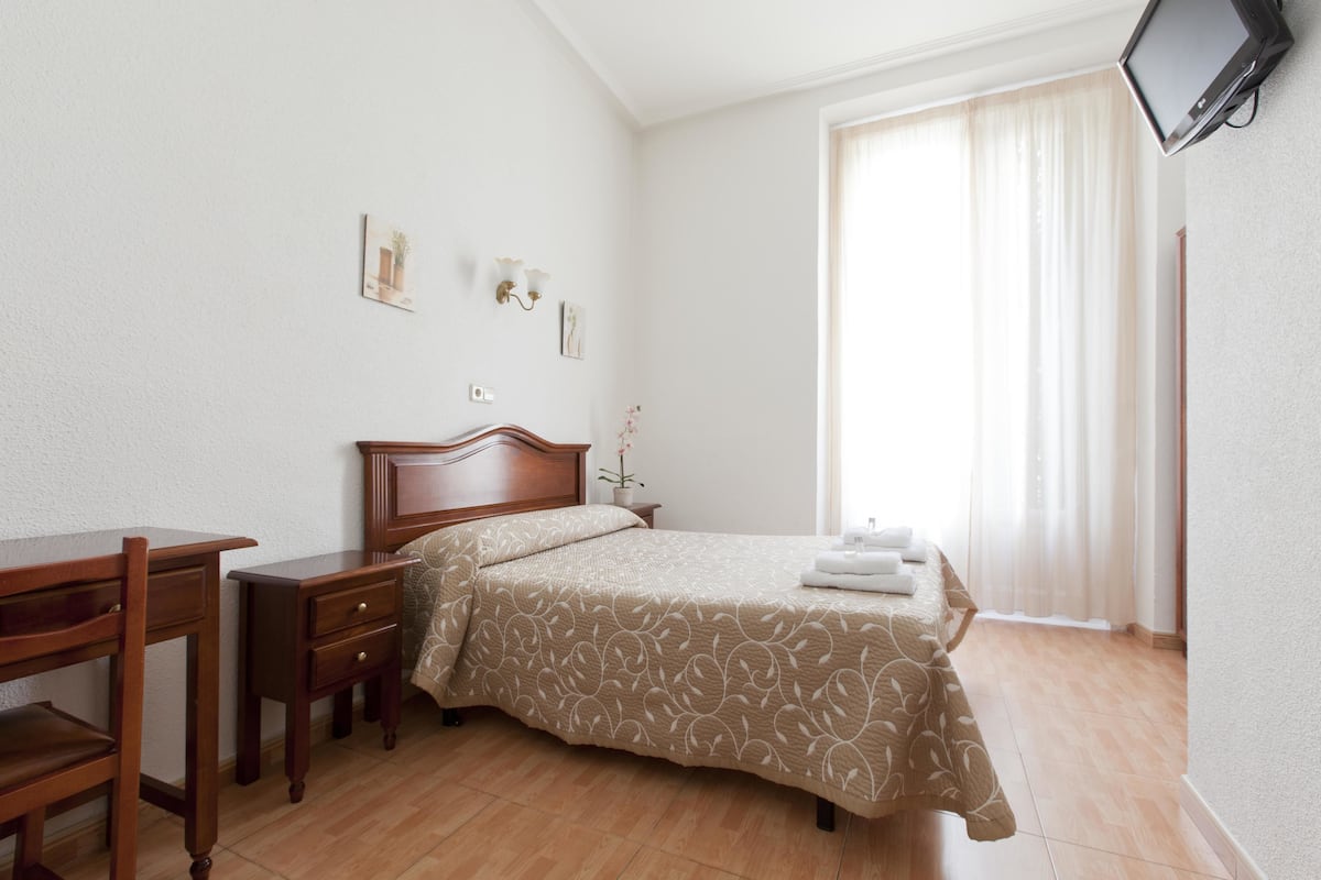 Escritorio, cortinas blackout y tabla de planchar con plancha