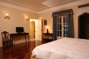 A hotel room with a large bed, a desk with a computer, a chair, and a lamp. - Stelares Boutique Hotel (Salta)