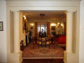 Uma sala de jantar formal com uma mesa comprida, cadeiras e um tapete estampado.