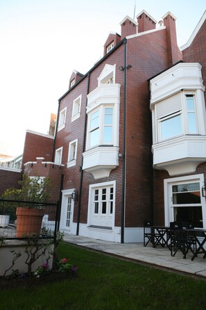 A two-story brick building with white-framed windows and a small balcony. - Stelares Boutique Hotel (Salta)