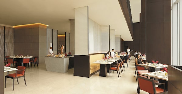 Un restaurante moderno con mesas y sillas altas, una barra central y vistas a la ciudad.