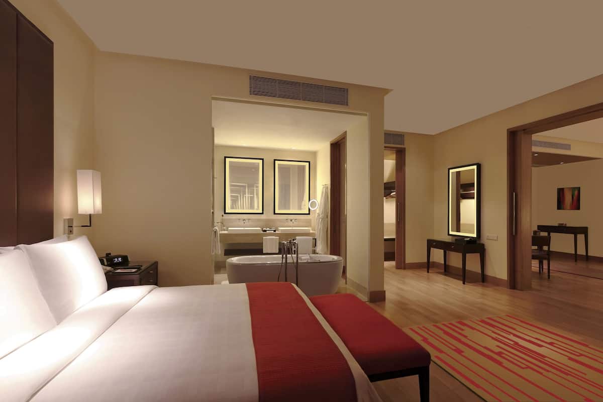 Une chambre d’hôtel dotée d’un grand lit, d’un coin salon, d’une salle de bain avec baignoire et d’un espace repas.