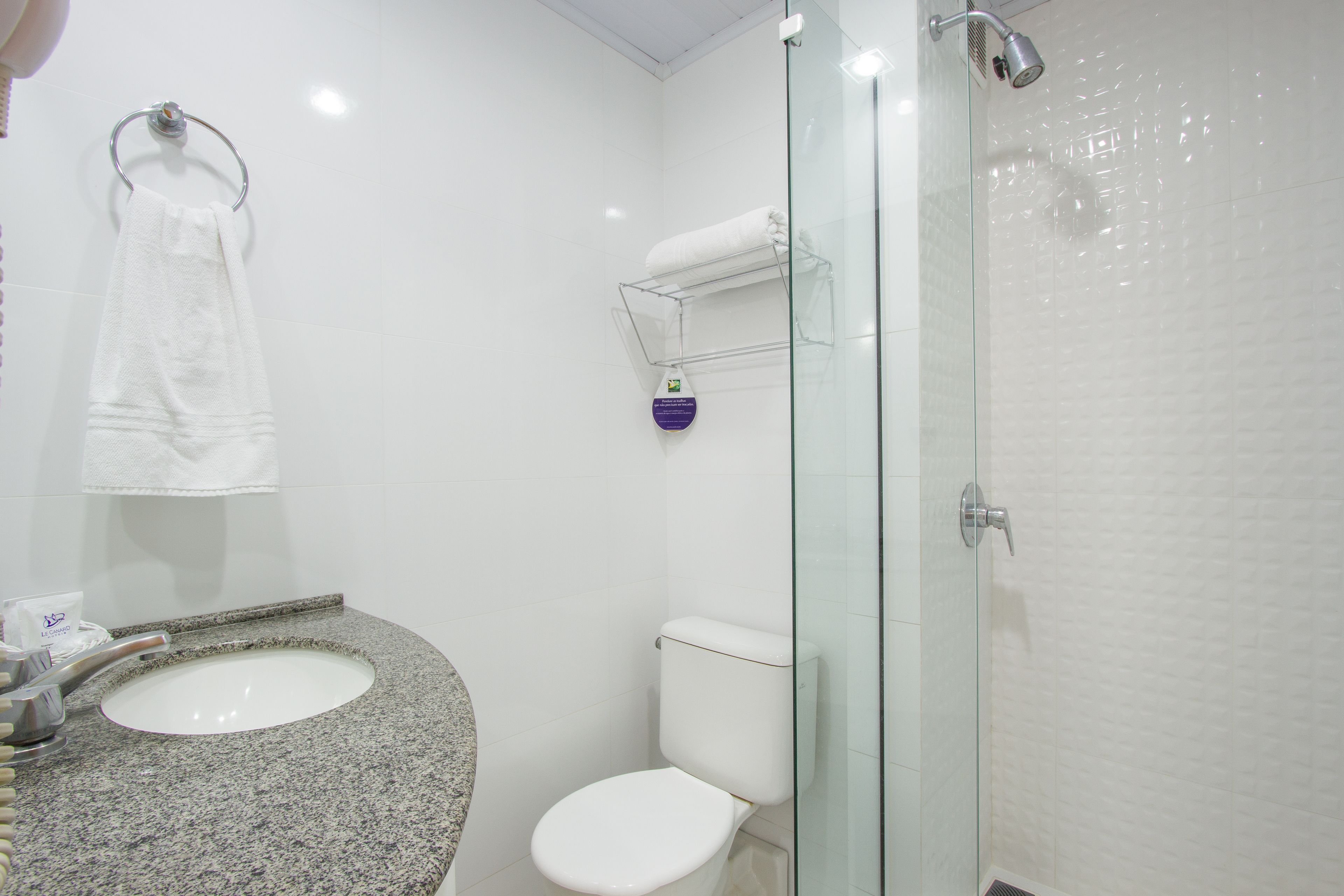 A bathroom with a granite sink, white toilet, and a glass-enclosed shower.