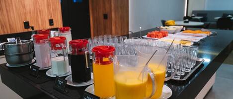 A buffet with various beverages and a fruit platter.
