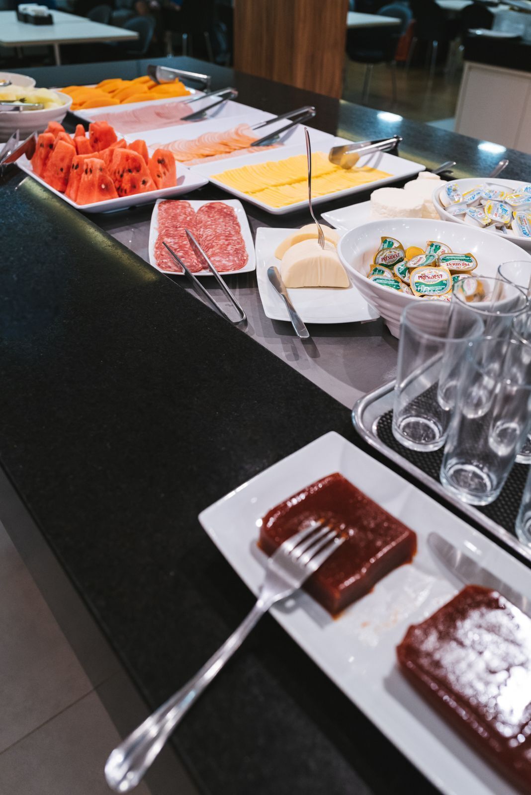 Un bufé con diversos alimentos, incluyendo sandía en rodajas, queso y carne.