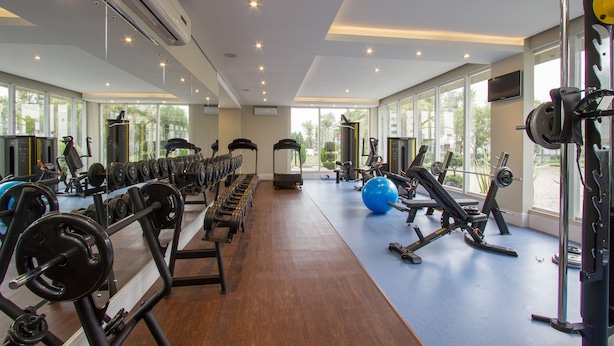 A gym with exercise equipment, large windows, and a blue floor. - Hotéis Le Canard (Lages)