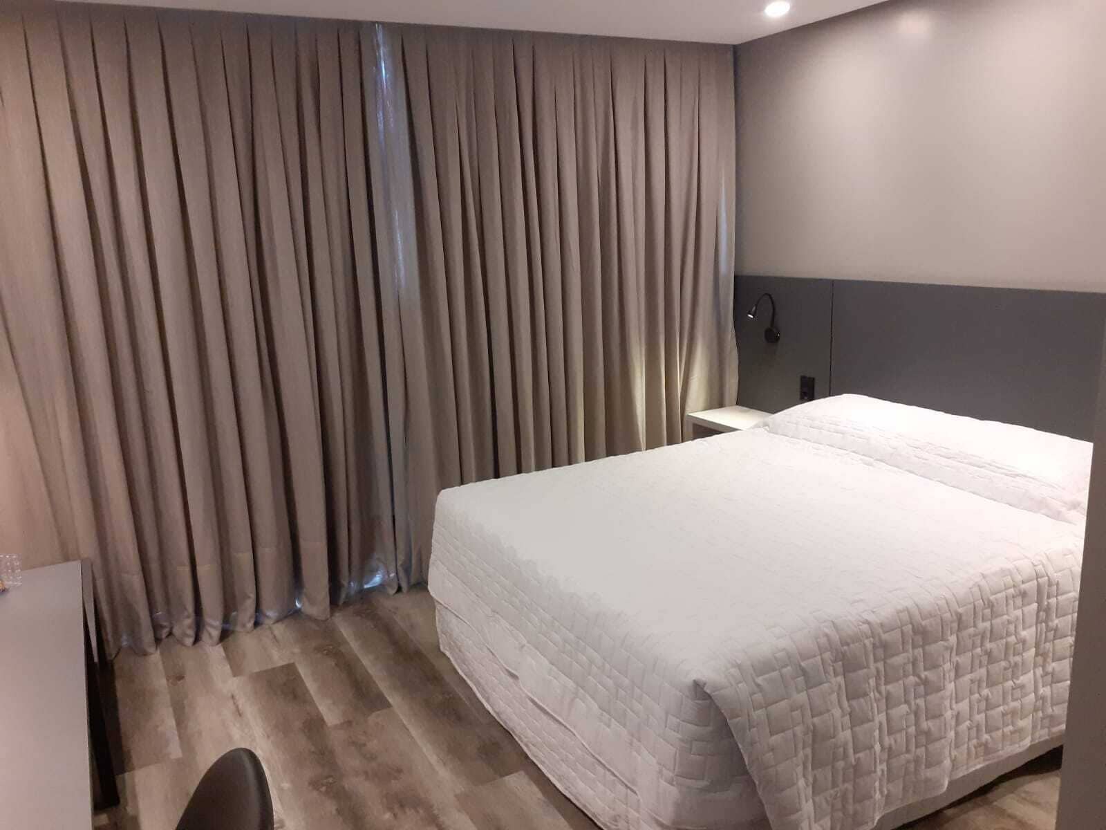 Una habitación de hotel con una cama grande, un escritorio y una cortina.