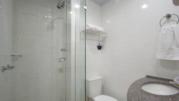 Ein Badezimmer mit einer gläsernen Duschkabine, einer weißen Toilette und einem Granitwaschbecken.