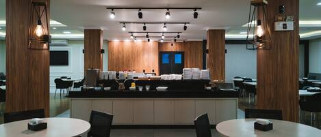 Un restaurant moderne doté d’un comptoir central, de plusieurs tables et de chaises.