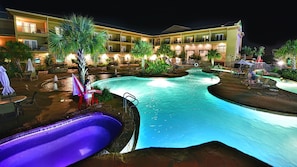 A hotel with a swimming pool, outdoor seating, and a guard standing by the pool.