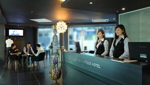 Un espace d’accueil d’hôtel au design moderne, comprenant un comptoir d’accueil, un coin salon et une grande fenêtre offrant une vue panoramique.