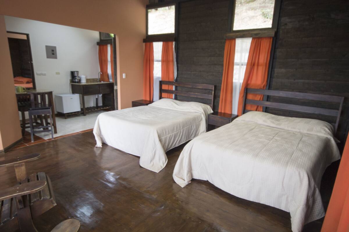 A room with two beds, a small desk, and a chair.