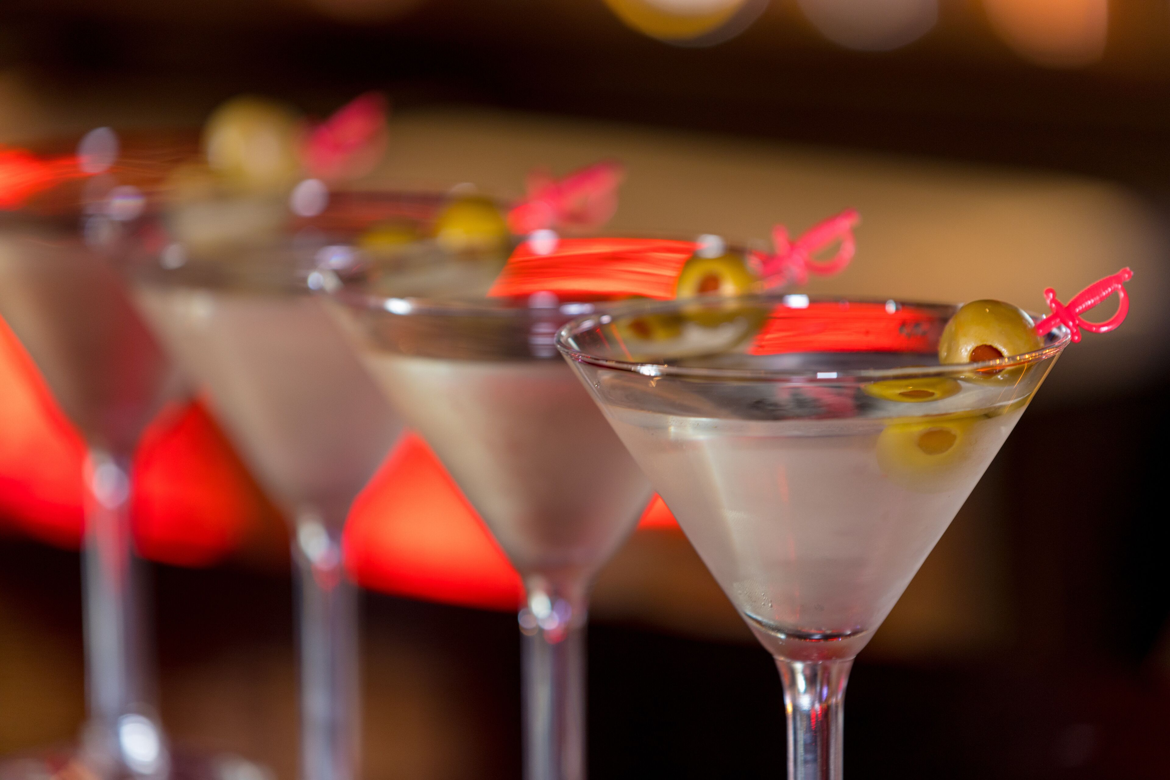Eine Bar mit mehreren Martini-Gläsern, jedes mit einer Olive und einer roten Schleife verziert.