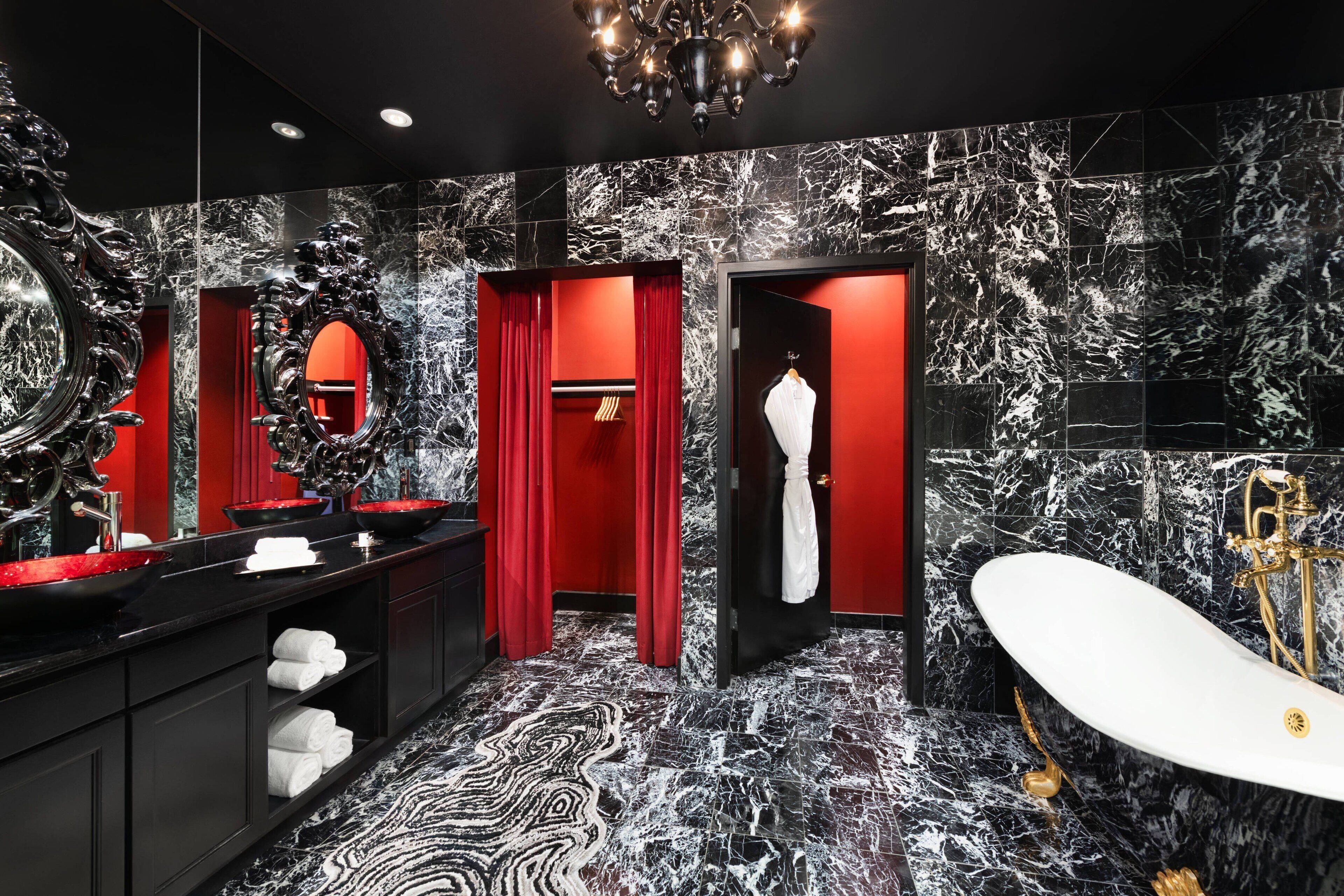 A luxurious bathroom with a black and white marble floor, a large mirror, a red curtain, and a white bathtub.