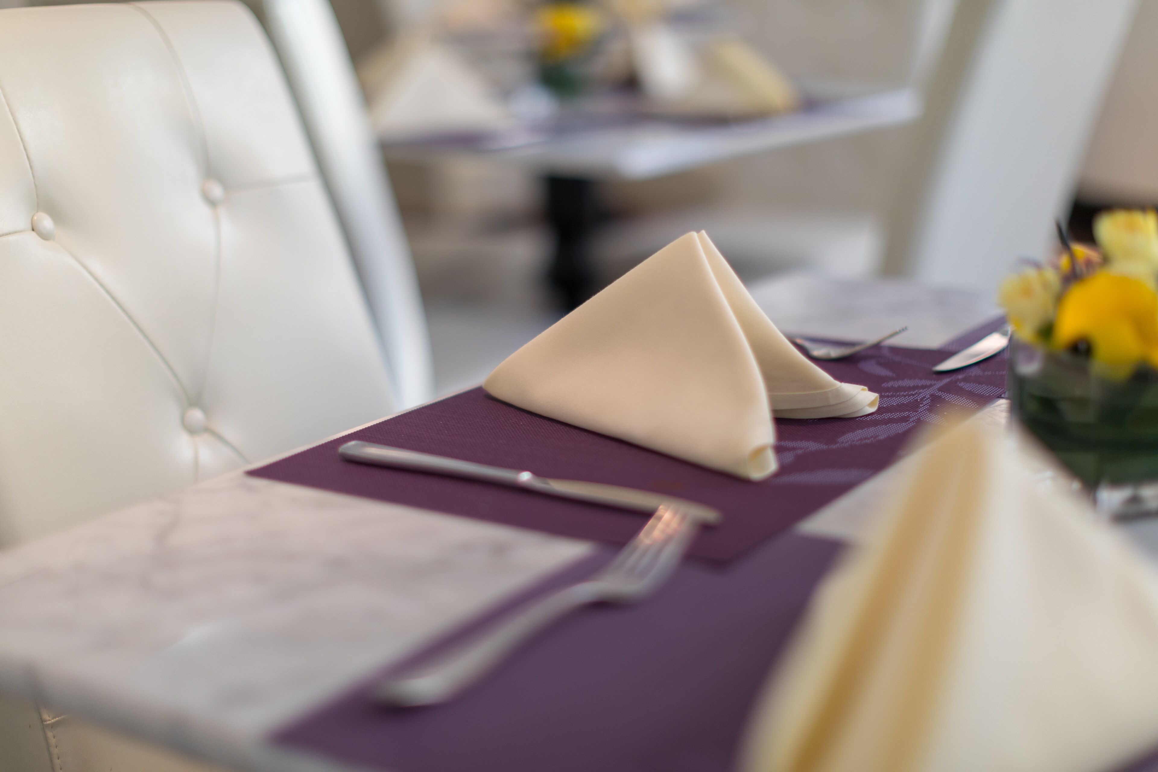 A neatly set dining table with a folded napkin, a fork, and a menu.