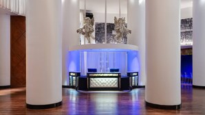A lobby with a reception desk, two decorative angel statues, and a blue-lit reception area. - The Saint Hotel, New Orleans, French Quarter (New Orleans)
