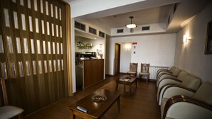 Una sala de estar con un separador de madera, un comedor con mesa y sillas, y una cocina al fondo.