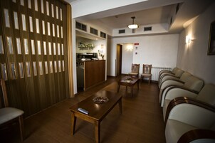A living room with a wooden partition, a dining area with a table and chairs, and a kitchen in the background.