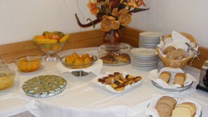 Una mesa de buffet con diversos alimentos, como frutas, pasteles y pan.