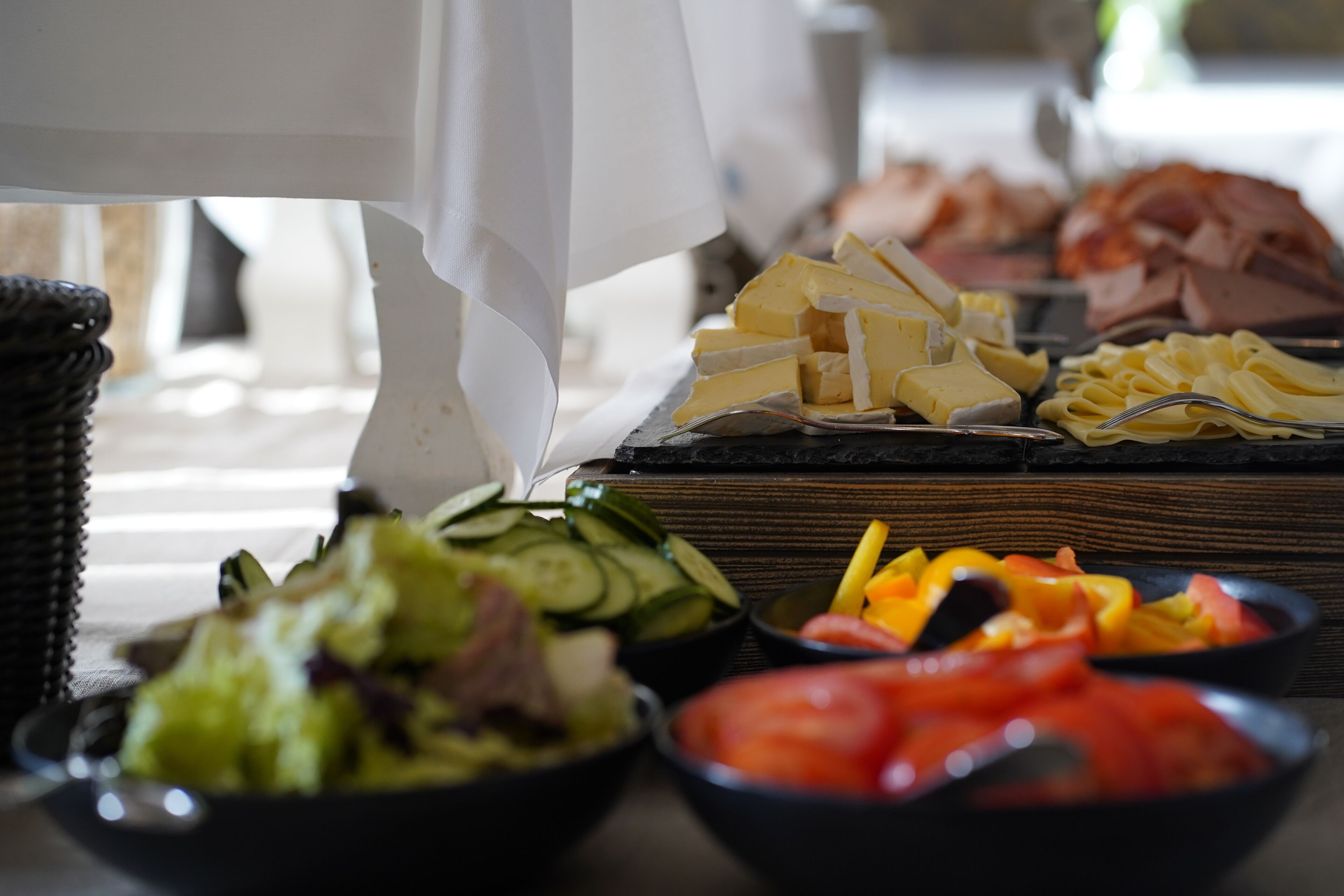 A buffet table with various food items including cheese, ham, vegetables, and salads.