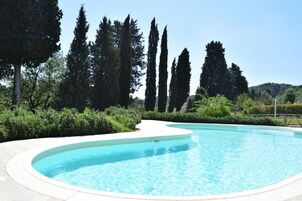 Una piscina al aire libre, sillones reclinables de piscina
