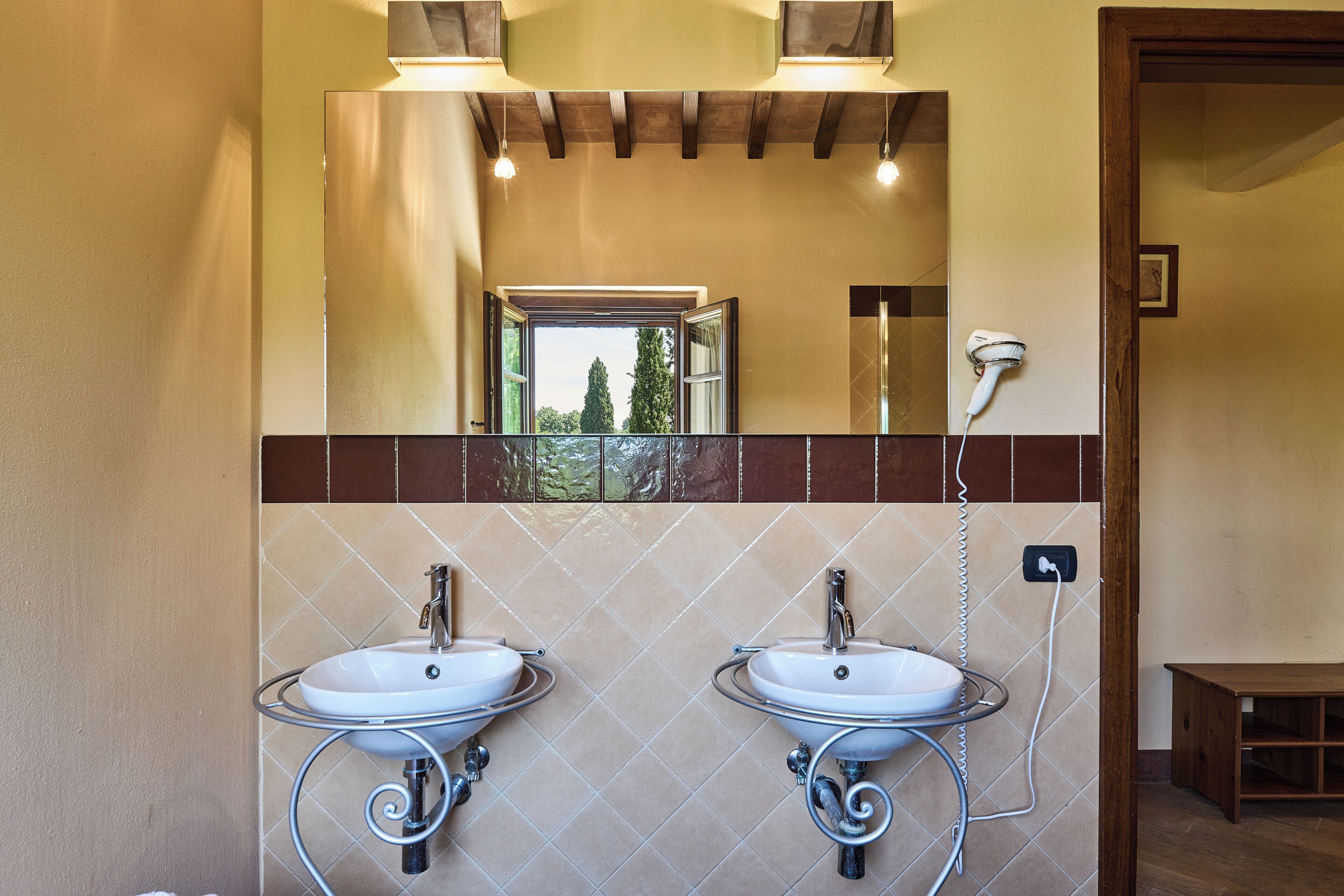 A bathroom with two sinks, a mirror, and a hairdryer.