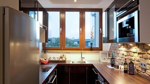 Een moderne keuken met een groot eiland, roestvrijstalen apparatuur en een steen achterwand.
