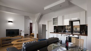 Een moderne woonkamer met een leren zwarte bank, een glazen salontafel en een flatscreen televisie.