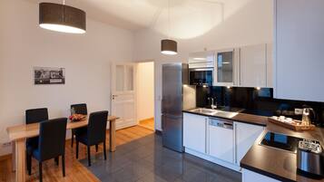 A modern kitchen with a central island, stainless steel appliances, and a dining area with a wooden table and chairs.