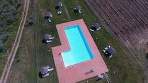 An aerial view of a rectangular swimming pool with a red border, surrounded by grass and trees. - Agriturismo Poggio Corbello (Massa Marittima)