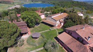 An aerial view of a rural property with a large pond, stone buildings, and a well-maintained garden. - Agriturismo Poggio Corbello (Massa Marittima)