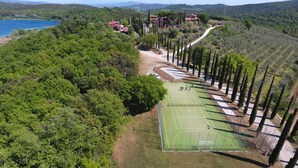 An aerial view of a tennis court surrounded by dense greenery and a few buildings. - Agriturismo Poggio Corbello (Massa Marittima)