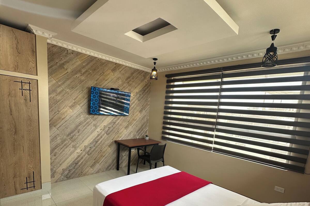 A hotel room with a bed, a desk, and a wardrobe.